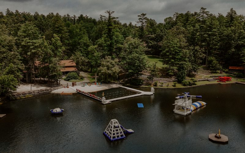 Aerial view of Camp Pinnacle's elevated lakefront and facilities surrounded by forested mountains in Flat Rock, North Carolina